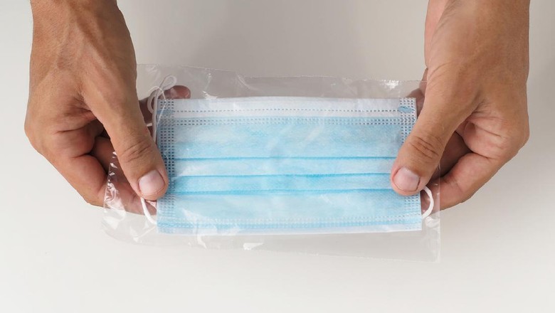 Cara Menyimpan Masker Hands holds new protective face mask In transparent pouch. Close-up shot.