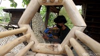 Seorang perajin sedang menyelesaikan pembuatan hiasan dinding dari limbah kayu.