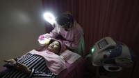 Pelayanan salon dan tempat cukur rambut kini diperbolehkan selama selama masa Pembatasan Sosial Berskala Besar ( PSBB Transisi) masa transisi. Dr Ferlinna dengan APD tengah melakukan perawatan kecantikan kepada konsumen.