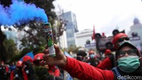 Salah satu buruh menyalakan flare di tengah-tengah aksi.
