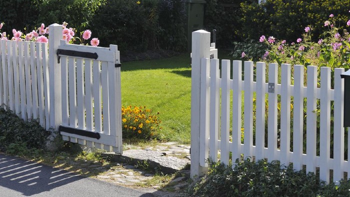 Spacious white house with wooden decoration on garage and wood style fence