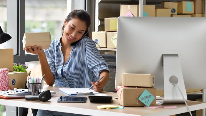 Working women at their store. They wearing casual clothing, accepting new orders online and packing merchandise for customer