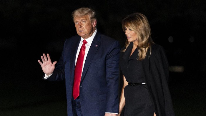 President Donald Trump, accompanied by first lady Melania Trump, waves as he walks from Marine One on the South Lawn of the White House, early Friday, Oct. 23, 2020, in Washington. Trump is returning from a debate in Nashville, Tenn. (AP Photo/Alex Brandon)