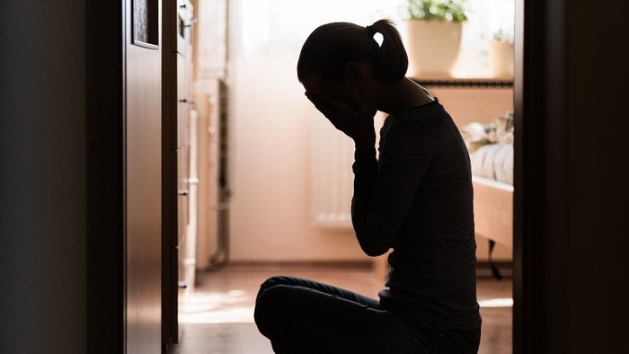 Ilustrasi wanita menangis Sad young woman sitting on room floor crying with hand over face