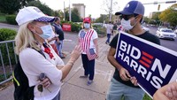 Meski menjadi debat pamungkas, kedua para pendukung Donald Trump (kiri) dan pendukung Joe Biden (kanan) tetap akur dan berbincang membahas masalah politik di depan Belmont University, Kamis, 22 Oktober 2020, di Nashville, Tenn waktu setempat. Foto: AP/Mark Humphrey