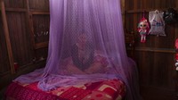Valentina Esperanza, yang baru sembuh dari demam berdarah, duduk di tempat tidurnya terlindung oleh kelambu saat dia menonton program televisi di rumahnya di Pucallpa, Ucayali, Peru.