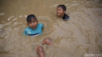 Anak-anak memanfaatkan banjir untuk bermain.