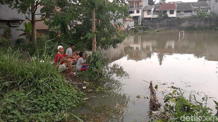 Warga manfaatkan lapang sepak bola yang terendam banjir untuk memancing.