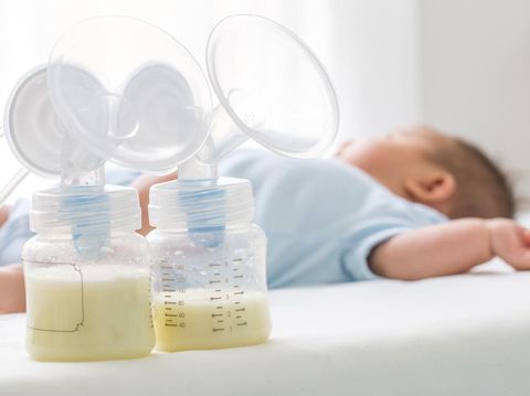 Breast milk pump and baby lying on the white bed