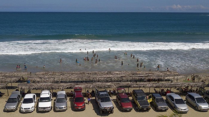 Corona Melandai, Pantai Venezuela Ramai Lagi Tourists' cars are parked along Los Angeles beach after it recently reopened following a lockdown to contain the spread of COVID-19 in La Guaira, Venezuela, Friday, Oct. 23, 2020. Strict quarantine restrictions forced the closure of beaches across the country in March and reopened this week. (AP Photo/Matias Delacroix)
