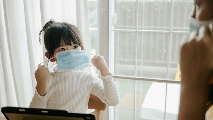 Asian businesswoman wearing protective face mask while working with laptop to protect pollution from dust PM2.5 and coronavirus covid-19