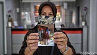 Pendaftar menunjukkan foto diri di depan tempat usahanya saat mendartar BLT UMKM.