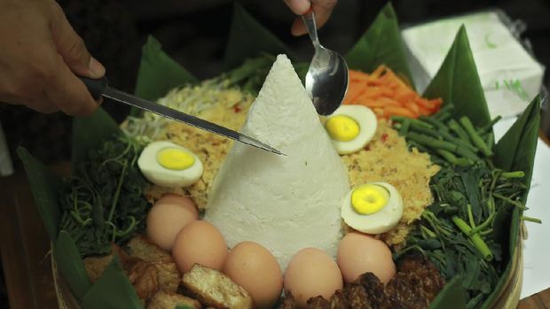 Potong Tumpeng. Beautiful Javanese Nasi Tumpeng. Indonesian Traditional Food, made from rice and coconut milk with chicken, vegetables, tempe, and more