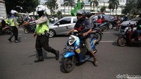 Polisi memberhentikan pengendara yang melanggar lalu lintas. 