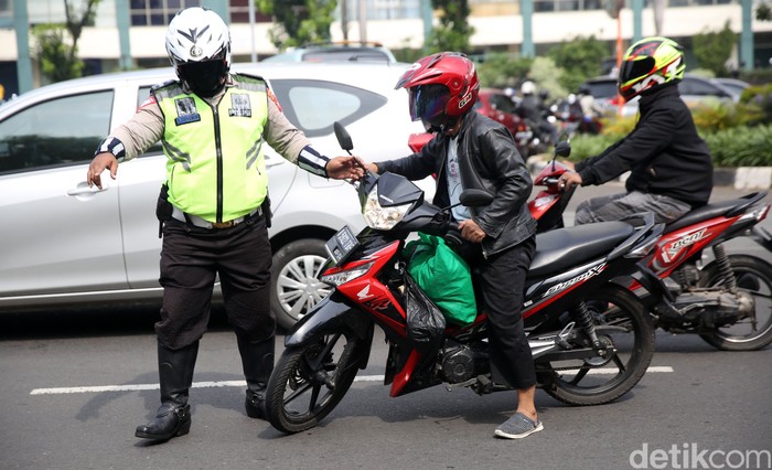Anggota Polisi Satua Lalu Lintas Polres Jakarta Timur melakukan razia kendaraan bermotor di Jalan DI Panjaitan, Cawang, Jakarta Timur, Senin (26/10/2020). Operasi Zebra 2020 mulai digelar Senin (26/10). Ada lima jenis pelanggaran yang menjadi prioritas sasaran penindakan dalam operasi yang akan berlangsung hingga 8 November mendatang.