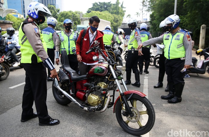 Anggota Polisi Satua Lalu Lintas Polres Jakarta Timur melakukan razia kendaraan bermotor di Jalan DI Panjaitan, Cawang, Jakarta Timur, Senin (26/10/2020). Operasi Zebra 2020 mulai digelar Senin (26/10). Ada lima jenis pelanggaran yang menjadi prioritas sasaran penindakan dalam operasi yang akan berlangsung hingga 8 November mendatang.