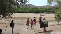 Pengunjung turis mancanegara berpose dengan papan taman nasional Komodo di Pulau Rinca.