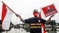 Seorang peserta aksi juga mengibarkan bendera merah putih.