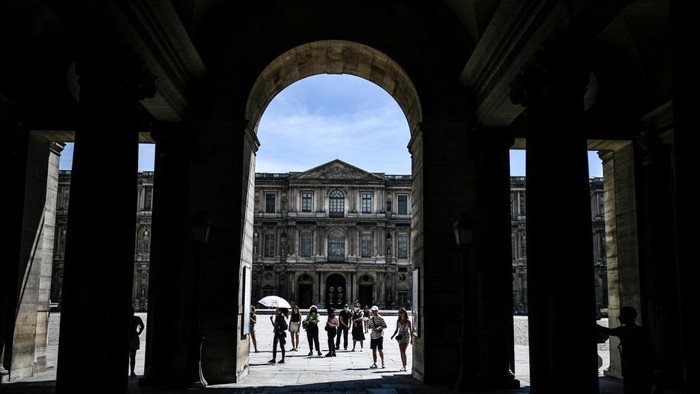 Tourists accompanied by a guide visit the exterior of the Louvre museum, in Paris on August 6, 2020. (Photo by STEPHANE DE SAKUTIN / AFP)