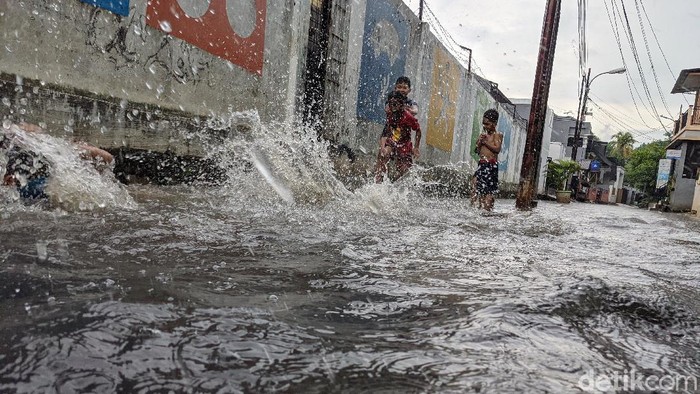 Anak-anak bermain di saluran air dan genangan air hujan di jalan Wijaya Timur, Petogogan, Jakarta Selatan, Selasa (27/10/2020).