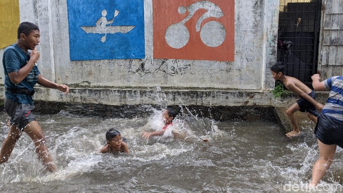 Genangan Air Jadi Hiburan Anak-Anak Petogogan Anak-anak bermain di saluran air dan genangan air hujan di jalan Wijaya Timur, Petogogan, Jakarta Selatan, Selasa (27/10/2020).