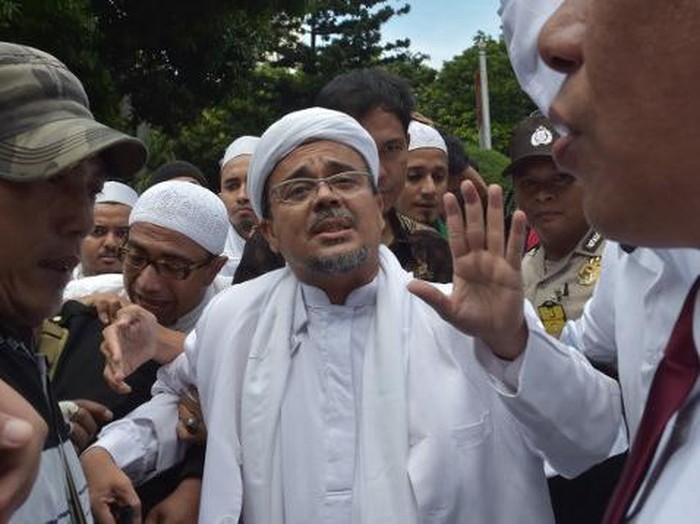 Rizieq Shihab, leader of the Indonesian hardline Muslim group FPI (Front Pembela Islam or Islamic Defender Front), arrives at the police headquarters in Jakarta on January 23, 2017. - Shihab was summoned as a witness by police over allegations he insulted rupiah bank notes by saying they contained communist symbols. (Photo by ADEK BERRY / AFP)
