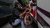 Tampak seorang penumpang sedang memasukan sepeda ke dalam bagasi bus.