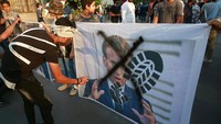 Di Irak, para pengunjuk rasa merusak foto Presiden Prancis Emmanuel Macron. Mereka menggelar demonstrasi di depan Kedutaan Besar Prancis, di Baghdad. AP Photo/Khalid Mohammed  
