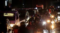 Sejumlah pengendara motor tampak menggunakan jas hujan saat terjebak macet.