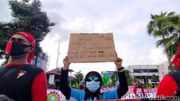Sejumlah demonstran tampak membawa poster berisi penolakan mereka serta kritik terhadap DPR atas disahkannya omnibus law UU Cipta Kerja.