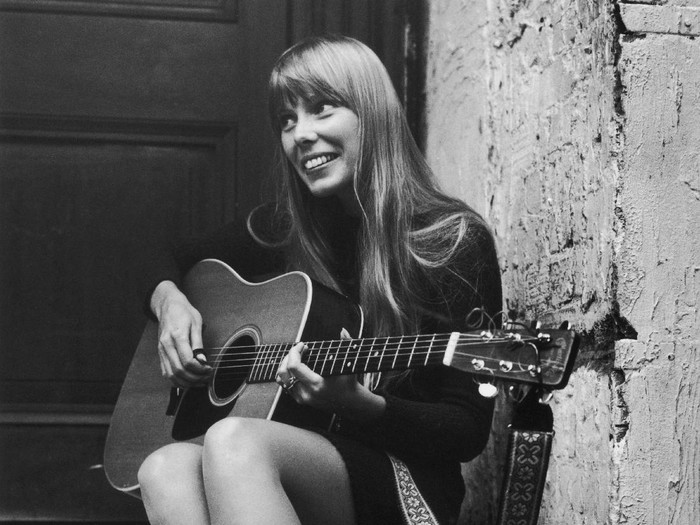 18th September 1968:  Canadian folk singer and songwriter Joni Mitchell, strumming her guitar outside The Revolution club in London.  (Photo by Central Press/Getty Images)