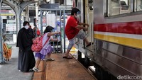 Seorang penumpang bersama dua anaknya memasuki KRL.