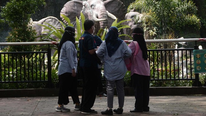 Pengunjung berposse di kandang Gajah sumatera saat mengisi waktu libur di Taman Margasatwa Ragunan, Jakarta