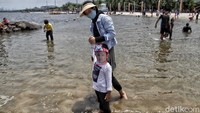 Guna mencegah penyebaran virus Corona, tampak sejumlah wisatawan mengenakan masker maupun face shield atau pelindung wajah saat berkunjung ke Pantai Ancol.