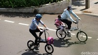 Seorang anak membonceng anaknya membelah sepinya jalan Sudirman, Jakarta.
