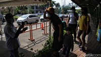 Seorang pengunjung diukur suhu tubuhnya.
