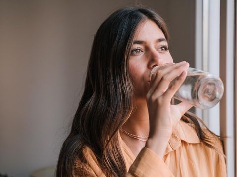 young beautiful woman by the window at home drinking water. Lifestyle
