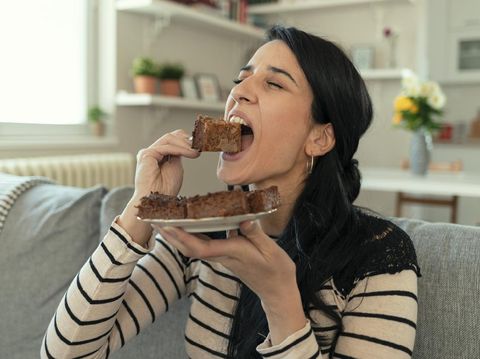 Young Woman Eating Unhealthy Food. Sweetness Indulging and Fattening Concept. Girl Biting Chocolate Cake, High-calorie Sweet Food, Increased Glucose Diabetes. Sweet food addiction.