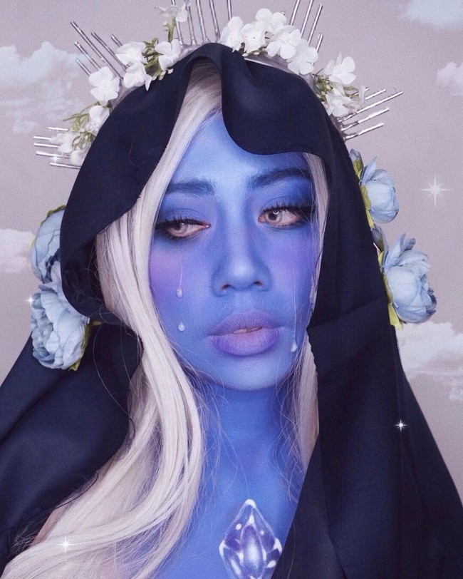 Terinspirasi dari karakter Blue Diamond dari serial kartun Steven Universe, beauty influencer Mega Chintasih melapisi wajahnya dengan face painting warna biru. Penampilannya semakin total dengan aksesori rambut dan bunga-bungaan.  Foto: Instagram