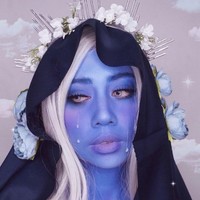 Terinspirasi dari karakter Blue Diamond dari serial kartun Steven Universe, beauty influencer Mega Chintasih melapisi wajahnya dengan face painting warna biru. Penampilannya semakin total dengan aksesori rambut dan bunga-bungaan.  Foto: Instagram
