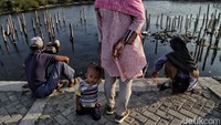 Seorang anak bersama orangtuanya bersantai di pinggir pantai.
