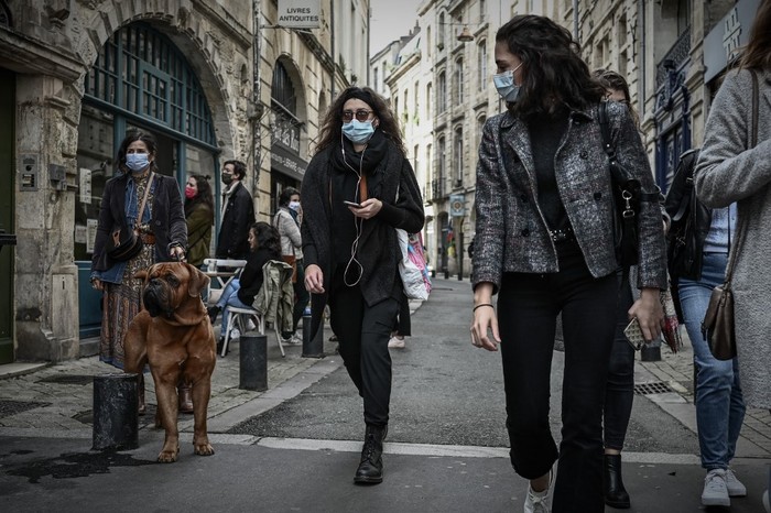 Pedestrians wearing protective face masks walk in a street of Bordeaux on October 29, 2020, as a new Covid-19 lockdown comes into effect at midnight. - French President announced on October 28 a new lockdown aimed at halting an alarming acceleration of Covid-19 cases, to take effect from October 29 night until 