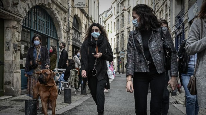 Pedestrians wearing protective face masks walk in a street of Bordeaux on October 29, 2020, as a new Covid-19 lockdown comes into effect at midnight. - French President announced on October 28 a new lockdown aimed at halting an alarming acceleration of Covid-19 cases, to take effect from October 29 night until 