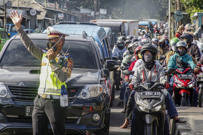 Polisi mengatur lalu lintas kendaraan yang  memadati ruas jalan jalur Wisata Puncak,  Kabupaten Bogor, Jawa Barat,  Sabtu (31/10/2020). Pada cuti bersama serta libur panjang Maulid Nabi Muhammad SAW hari ke-empat jalur wisata Puncak Bogor masih dipadati kendaraan wisatawan, Sat Lantas Polres Bogor memberlakukan rekayasa lalu lintas sistem satu jalur atau one way untuk mengurai kepadatan kendaraan. ANTARA FOTO/Yulius Satria Wijaya/hp.