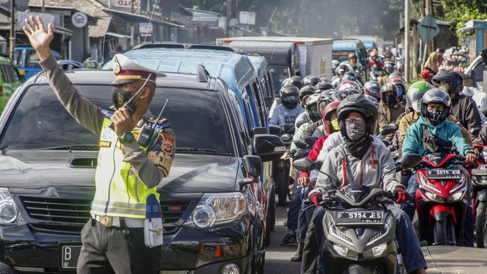 Polisi mengatur lalu lintas kendaraan yang  memadati ruas jalan jalur Wisata Puncak,  Kabupaten Bogor, Jawa Barat,  Sabtu (31/10/2020). Pada cuti bersama serta libur panjang Maulid Nabi Muhammad SAW hari ke-empat jalur wisata Puncak Bogor masih dipadati kendaraan wisatawan, Sat Lantas Polres Bogor memberlakukan rekayasa lalu lintas sistem satu jalur atau one way untuk mengurai kepadatan kendaraan. ANTARA FOTO/Yulius Satria Wijaya/hp.