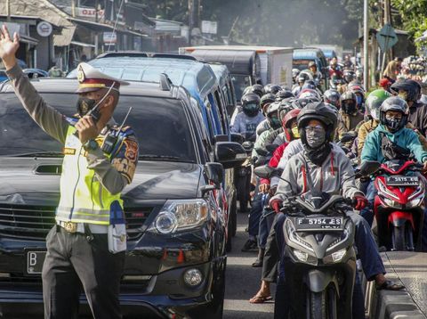 Polisi mengatur lalu lintas kendaraan yang  memadati ruas jalan jalur Wisata Puncak,  Kabupaten Bogor, Jawa Barat,  Sabtu (31/10/2020). Pada cuti bersama serta libur panjang Maulid Nabi Muhammad SAW hari ke-empat jalur wisata Puncak Bogor masih dipadati kendaraan wisatawan, Sat Lantas Polres Bogor memberlakukan rekayasa lalu lintas sistem satu jalur atau one way untuk mengurai kepadatan kendaraan. ANTARA FOTO/Yulius Satria Wijaya/hp.