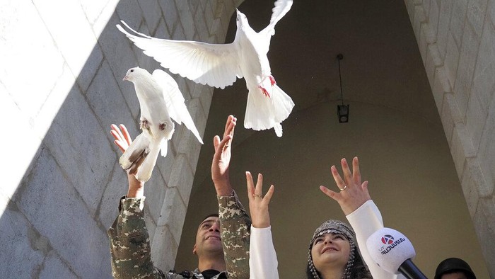 Tentara Langsungkan Pernikahan di Tengah Perang Armenia-Azerbaijan Newlyweds, soldier Hovhannes Hovsepyan, left, and Mariam Sargsyan walk after their wedding ceremony in the Holy Savior Cathedral, damaged by shelling by Azerbaijan's artillery during a military conflict in Shushi, the separatist region of Nagorno-Karabakh, Saturday, Oct. 24, 2020. The wedding was celebrated even as intense fighting in the region has continued. (AP Photo)