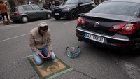 Seorang warga Paris berdoa di tepi jalan. Gilles Bouquillon/Getty Images.