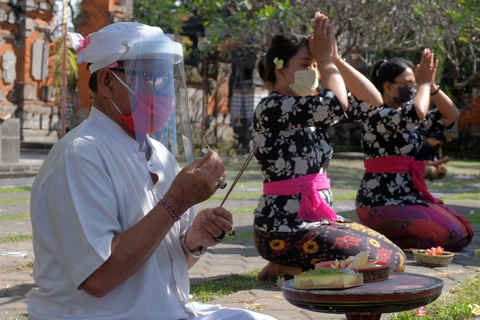 Tiga warga menggunakan masker saat turut berkeliling kampung dalam tradisi Ngerebeg di Desa Tegallalang, Gianyar.