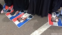 Saat aksi berlangsung, masa aksi perempuan menginjak-nginjak poster Presiden Prancis Emmanuel Macron.